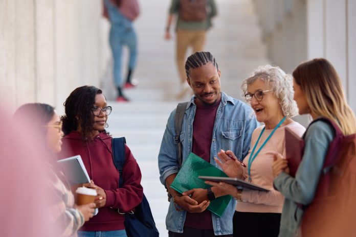 Multiracial group of students and their professor communicating in a hallway. Inside MBA admissions
