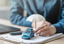 The Real Cost of a Car: Why Insurance Should Influence Your Choice Car insurance protect concept. Insurance agent. Insurance protection concept. A person is holding a blue car under an umbrella. The umbrella is white and is placed on top of a piece of paper.