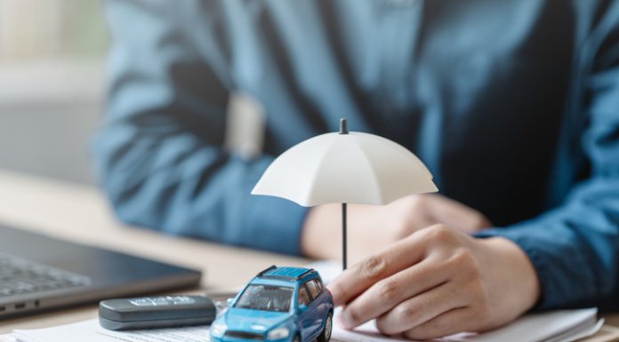 Car insurance protect concept. Insurance agent. Insurance protection concept. A person is holding a blue car under an umbrella. The umbrella is white and is placed on top of a piece of paper.