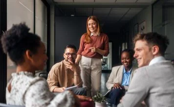 A group of motivated professionals sharing ideas, laughter, engagement, collaboration and collaboration in a bright office space, reflecting teamwork and creativity in a business environment.