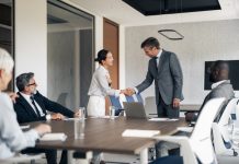 Multiracial business people shaking hands in a modern conference room during a corporate meeting, showing agreement and partnership in the professional workplace. Reach vs. Credibility in B2B marketing