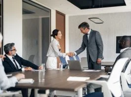 Multiracial business people shaking hands in a modern conference room during a corporate meeting, showing agreement and partnership in the professional workplace. Reach vs. Credibility in B2B marketing