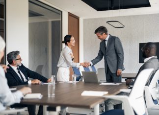 Multiracial business people shaking hands in a modern conference room during a corporate meeting, showing agreement and partnership in the professional workplace. Reach vs. Credibility in B2B marketing
