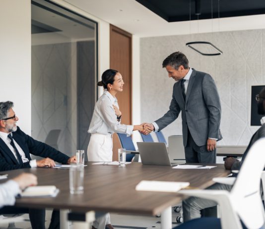 Multiracial business people shaking hands in a modern conference room during a corporate meeting, showing agreement and partnership in the professional workplace. Reach vs. Credibility in B2B marketing