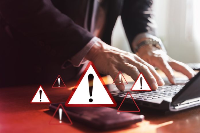 Cyber security warning alerts on laptop as businessman types, data breach risk concept cyberattack response strategy