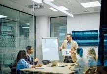Business leader presenting financial data to diverse team members during a corporate conference meeting in a modern office. Reach vs. Credibility in B2B marketing