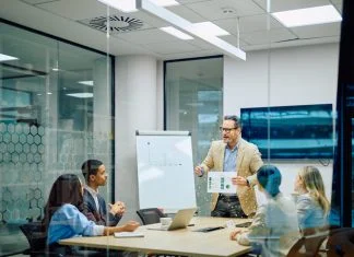 Business leader presenting financial data to diverse team members during a corporate conference meeting in a modern office. Reach vs. Credibility in B2B marketing