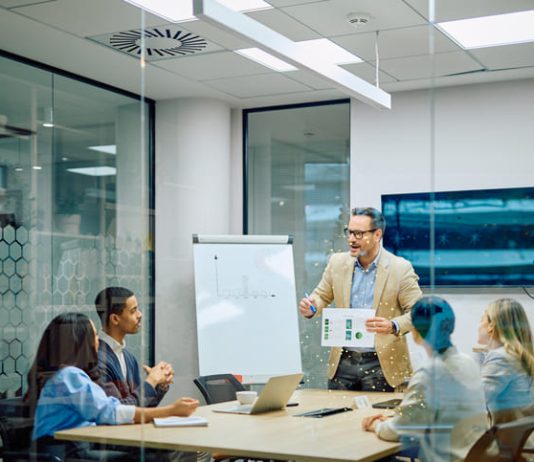 Business leader presenting financial data to diverse team members during a corporate conference meeting in a modern office. Reach vs. Credibility in B2B marketing