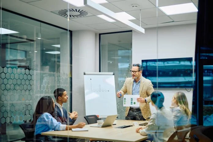 Business leader presenting financial data to diverse team members during a corporate conference meeting in a modern office. Reach vs. Credibility in B2B marketing