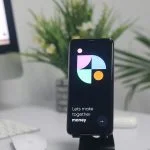 5 Reasons Why Buying Bitcoin (Probably) Still Makes Sense in 2026 a cell phone sitting on top of a stand on a desk for buying bitcoin