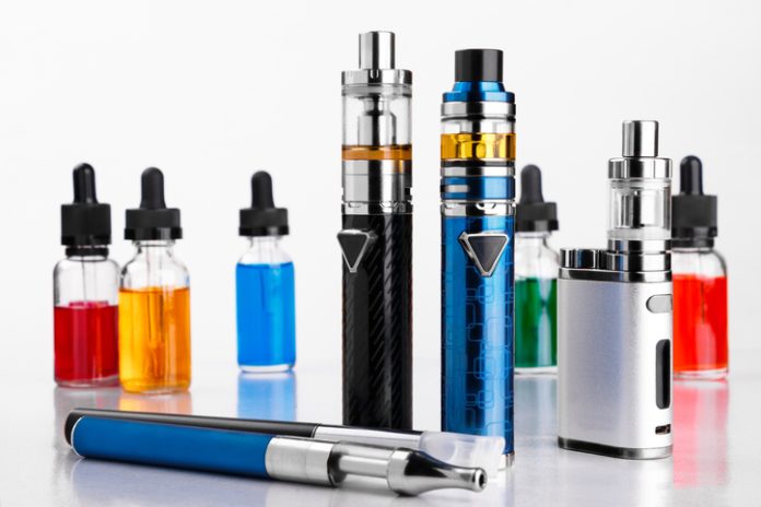 Modern electronic cigarettes, tobacco and bottles with assorted vape liquid on white background