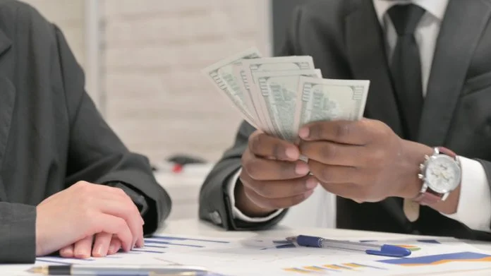 Close up of Businessman Giving Money to Female Business Partner CTO salary