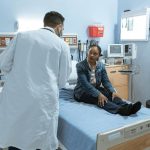 Doctor Talking to a Patient Sitting on Bed. Healthcare and the Workforce in US