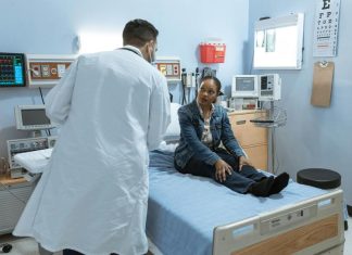 Doctor Talking to a Patient Sitting on Bed. Healthcare and the Workforce in US