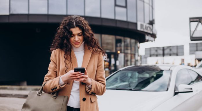 Car Insurance Explained: Why Third-Party Car Insurance Online is Mandatory Young woman using phone and standing by the car for car insurance