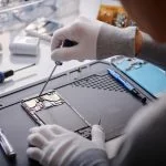 How to Test Phone Circuits Safely with a Magnetic Repair Mat and Professional Digital Multimeter Over shoulder shot of unrecognizable technician repairing disassembled smartphone, circuit with screwdriver