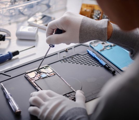 How to Test Phone Circuits Safely with a Magnetic Repair Mat and Professional Digital Multimeter Over shoulder shot of unrecognizable technician repairing disassembled smartphone, circuit with screwdriver