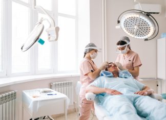 Professional trichologist surgeons carry out hair FUE Sapphire method hair transplant surgery in operating room to male patient with hair loss problem.