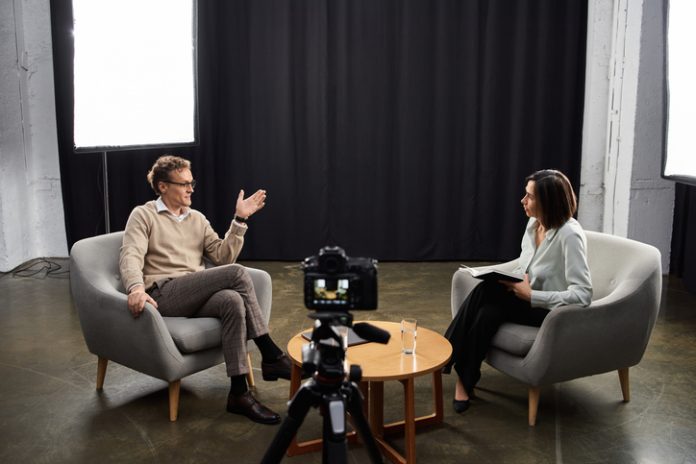 Engaging dialogue between journalist and guest in a cozy studio podcast setting Interview