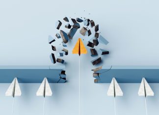 How Leaders Can Thrive Within the System by Meeting Fear Differently Fearless leader. Orange paper airplane breaking the wall barrier while others stuck, showing breakthrough, innovation, and leadership.