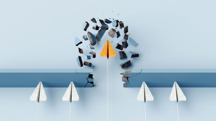 Fearless leader. Orange paper airplane breaking the wall barrier while others stuck, showing breakthrough, innovation, and leadership.