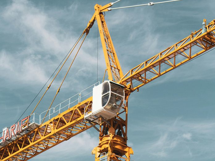 Yellow and black cranes during the day under cloudy skies