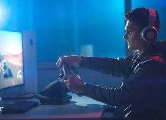 The guy gamer with headphones playing racing game on his personal computer