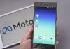 Mobile display with logo of Facebook, WhatsApp and Instagram apps in against blurred META logotype