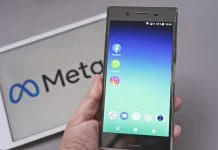 Mobile display with logo of Facebook, WhatsApp and Instagram apps in against blurred META logotype