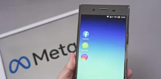 Mobile display with logo of Facebook, WhatsApp and Instagram apps in against blurred META logotype