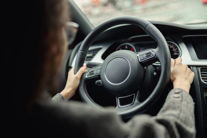 Back view of woman driver using turn signal in car while driving in city Steering wheel for fraud
