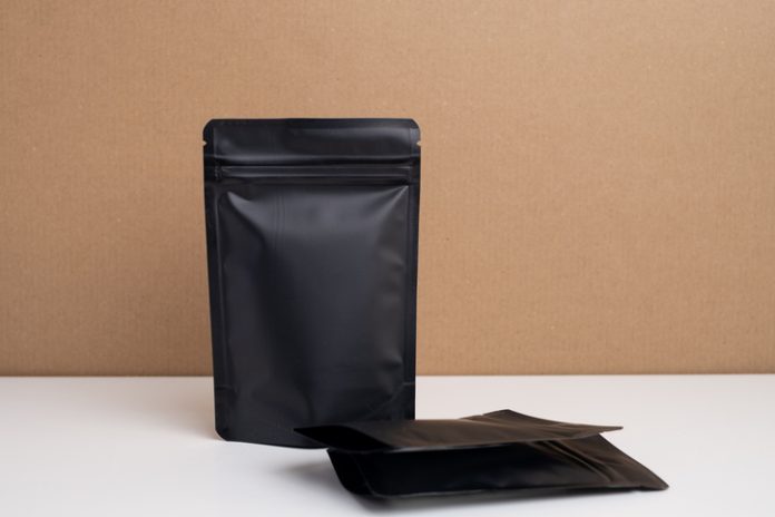 Black packages for tea, coffee, snacks and cosmetics in the background. Branding and packaging mockup for products. Packing closeup. Product for sale. Empty, mockup Branding and Flexible packaging mockup for products. Packing closeup. Product for sale. Empty, mockup