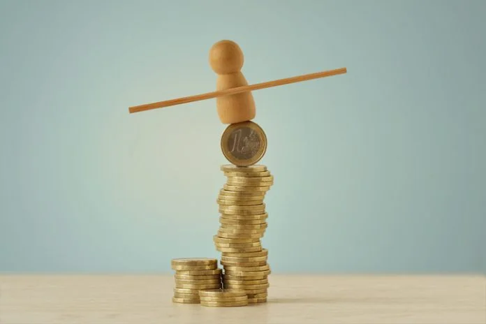 Wooden pawn balancing on piles of coins - Concept of economy and financial risk scaling clean power ventures