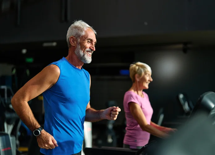 gym sport fitness exercising training mature man running cardio treadmill healthy active man adult woman equipment athletic couple run coach fit endurance Portrait of a senior man exercising in a gym. Protecting Men’s Lifelong Health concept