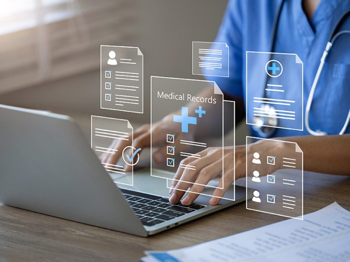 Doctor using laptop to manage electronic medical records. ambient listening