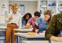 Female teacher observes students during an education exam at a high school.