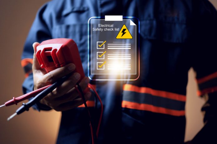 electrical safety concept with electric staff holding multimeter to check power source before start working on machine system or construction site