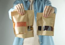 Woman with stand-up pouches of different products on light grey background