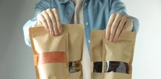 Woman with stand-up pouches of different products on light grey background