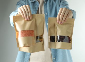 Woman with stand-up pouches of different products on light grey background