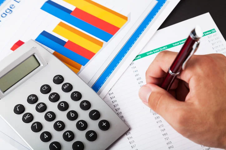 Close-up of a Businessman Analyzing Business Graphs with Calculator
