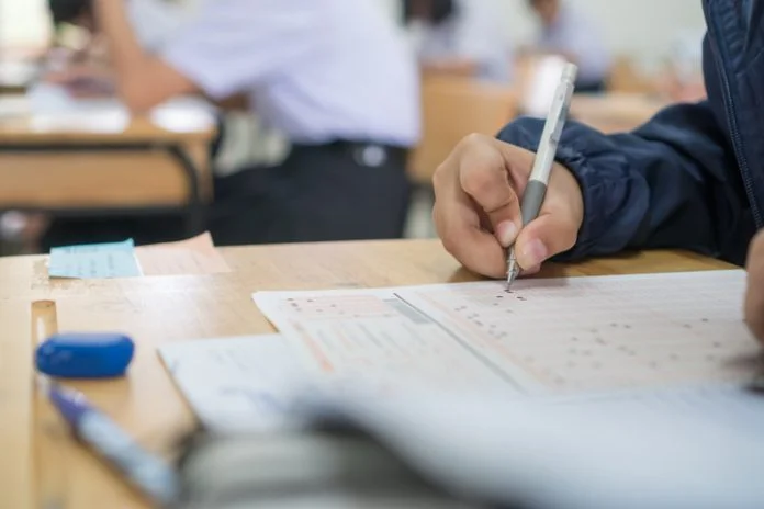 Group student testing in exercise taking fill in exam paper answer sheet with pencil at school or university in test room, document exams at campus classroom, education or back to school concept CAT4 Practice Test Year 7.