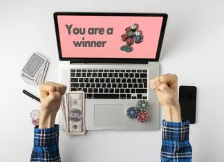 Overhead person playing the gamble games online at home and win the money, the stack of chips on the gadget screen
