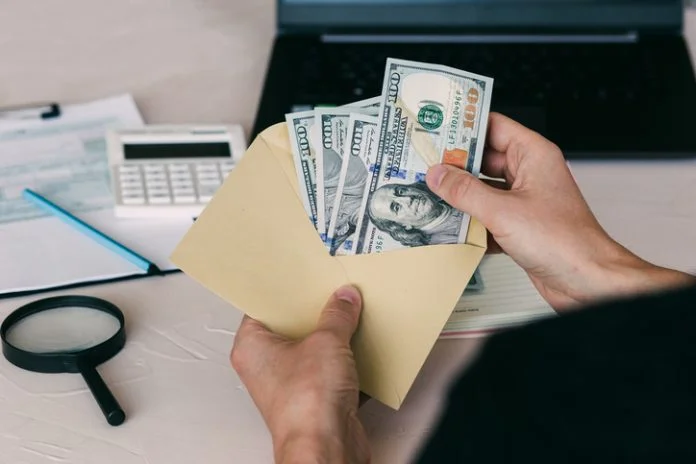 man's hand holds envelope with money Cash Before Payday