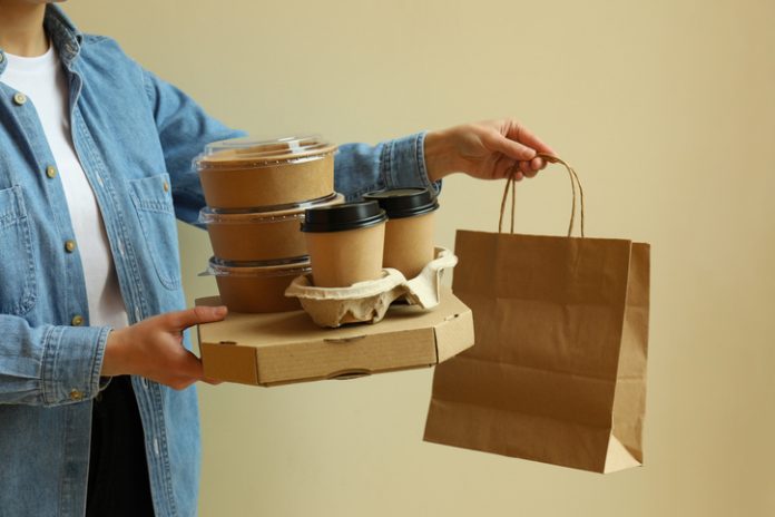 Woman hold delivery containers for takeaway food on beige background food packaging