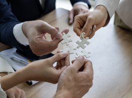 Business people work together to solve a jigsaw puzzle, representing the importance of teamwork and collaboration and business coalition