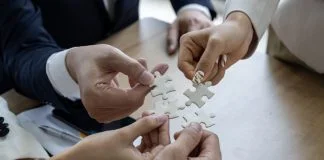 Business people work together to solve a jigsaw puzzle, representing the importance of teamwork and collaboration and business coalition
