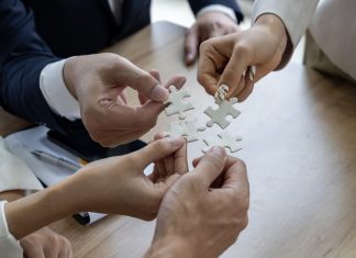 Business people work together to solve a jigsaw puzzle, representing the importance of teamwork and collaboration and business coalition