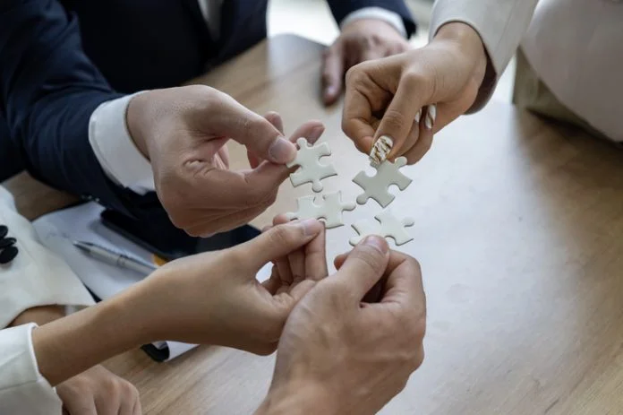 Business people work together to solve a jigsaw puzzle, representing the importance of teamwork and collaboration and business coalition