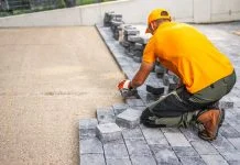 Worker Laying Cobblestones for a Patio in a Residential Backyard on a Sunny Day